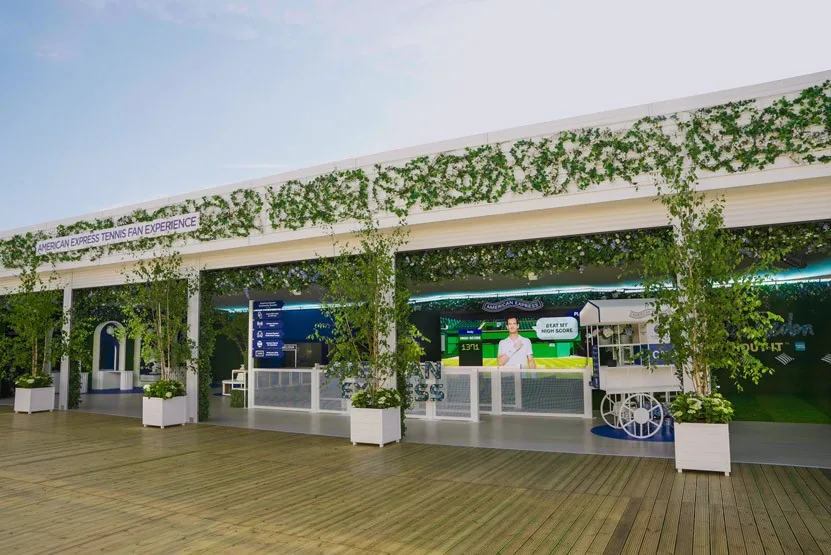 The American Express pavilion on the grounds, with hedges, planters and the games visible through the open front